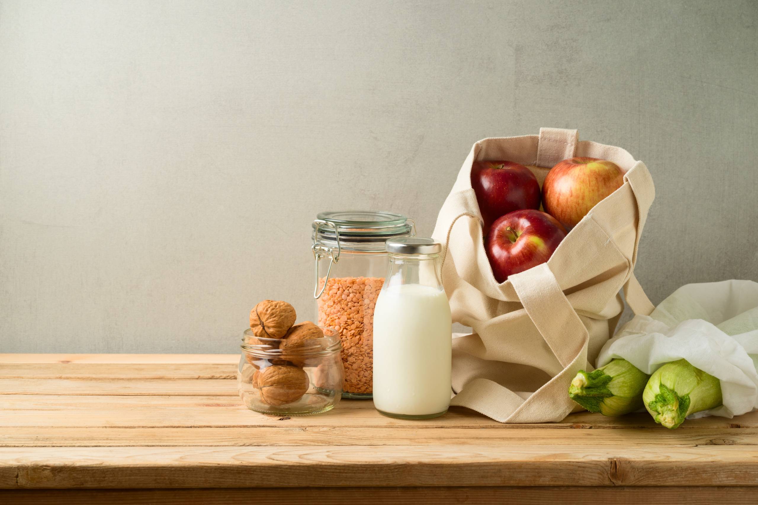 Wkladanie bananów i pomarańczy do wielorazowej torby na warzywa i owoce.