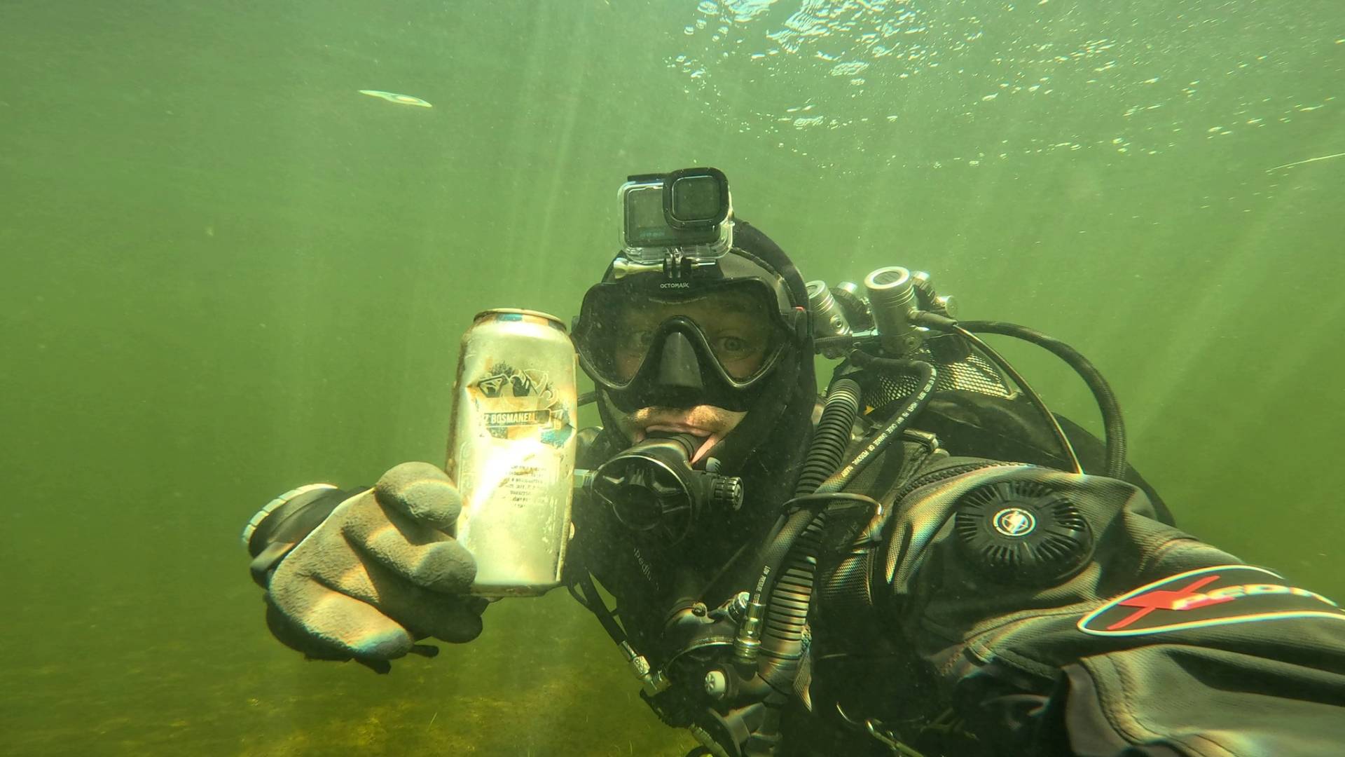 Nurek wyławia puszkę z dna rzeki podczas akcji sprzątania Odry i walki z zanieczyszczeniem wód